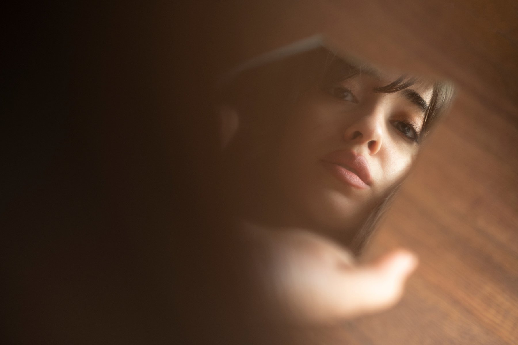 Emotional Young Woman Looking into Broken Mirror