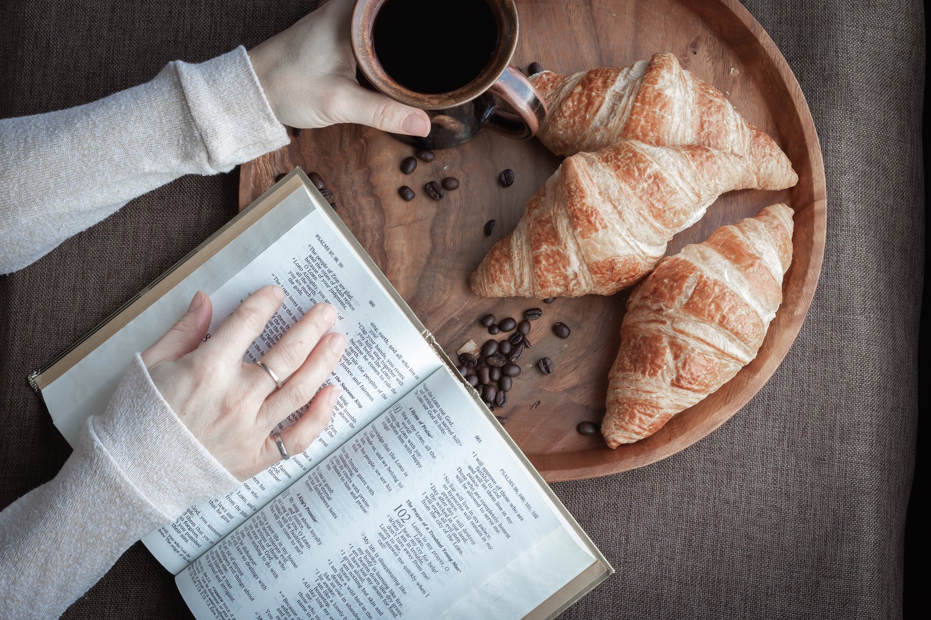 Reading bible with coffee and croissants